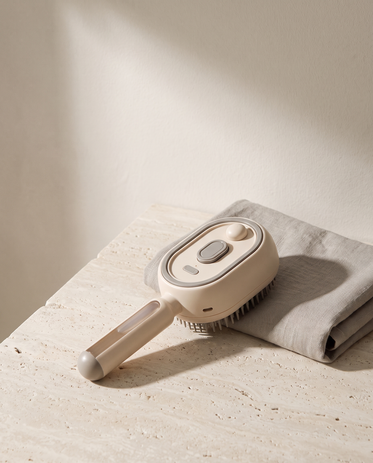 Brosse de massage du cuir chevelu posée sur une surface de travertin à côté d'une serviette en lin