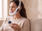 Femme sur son canapé qui porte le Bandeau Menton blanc et tient la télécommande sans fil, écran allumé