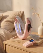 Bandeau Menton rose et sa télécommande sans fil sur une table de chevet en chêne, lumière de fin de journée