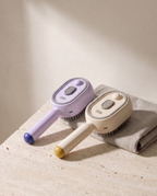 Duo de Brosses Vapo, une beige et une violette, posées sur du travertin