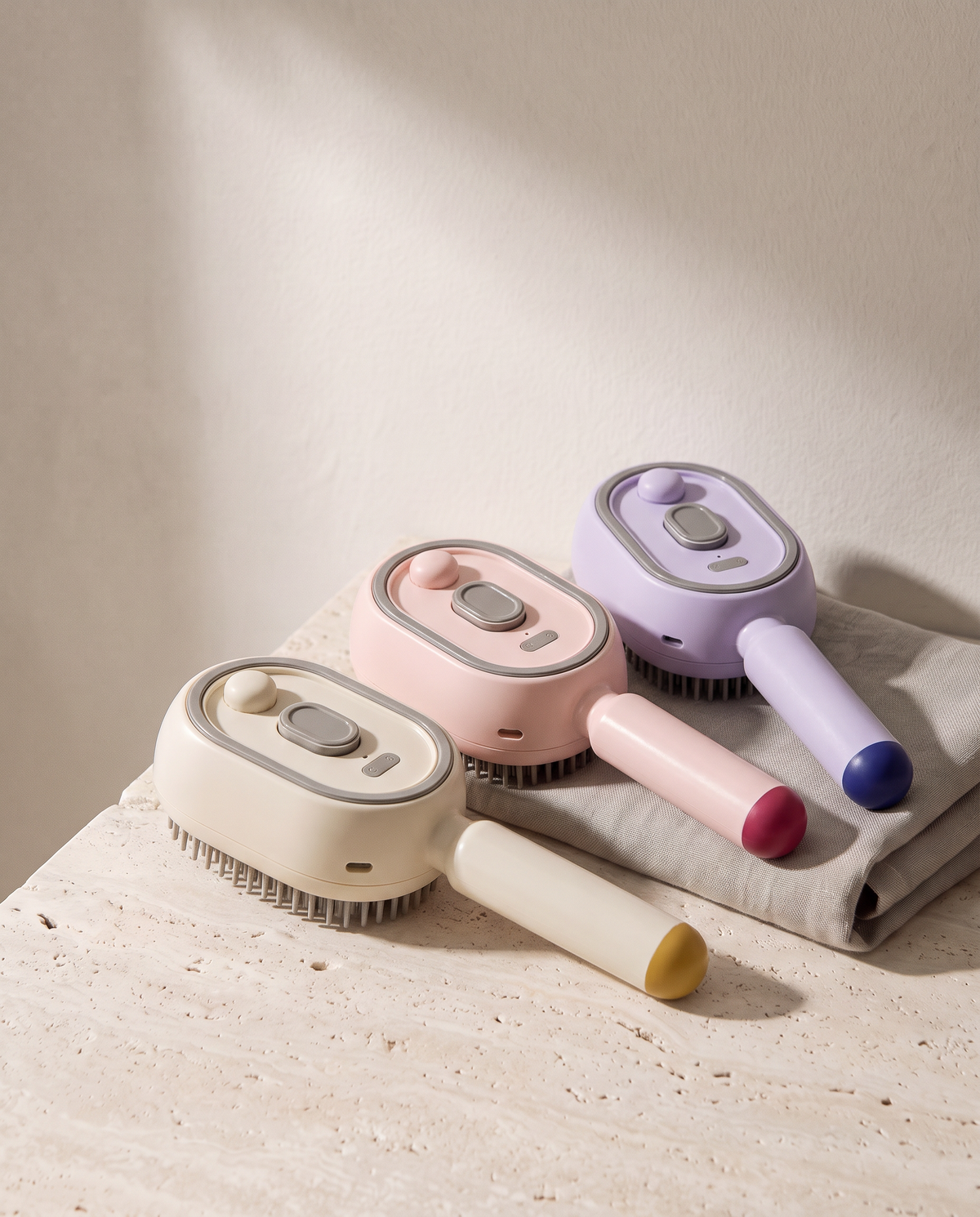 Les trois coloris de la Brosse Vapo côte à côte : beige, rose et violet