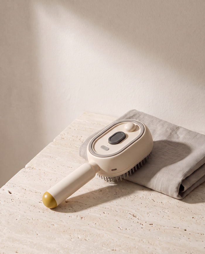 Brosse Vapo coloris beige, vue de trois quarts sur du travertin, serviette en lin à côté