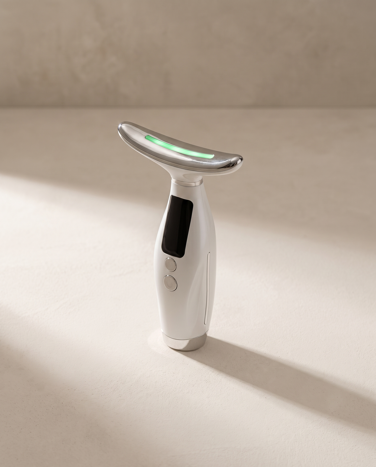 Lift Pro SCULVORA, appareil EMS visage et cou, coloris blanc nacré, posé sur un fond de plâtre écru