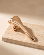 Rouleau Sculpt 4D SCULVORA finition dorée, posé sur une pierre de travertin