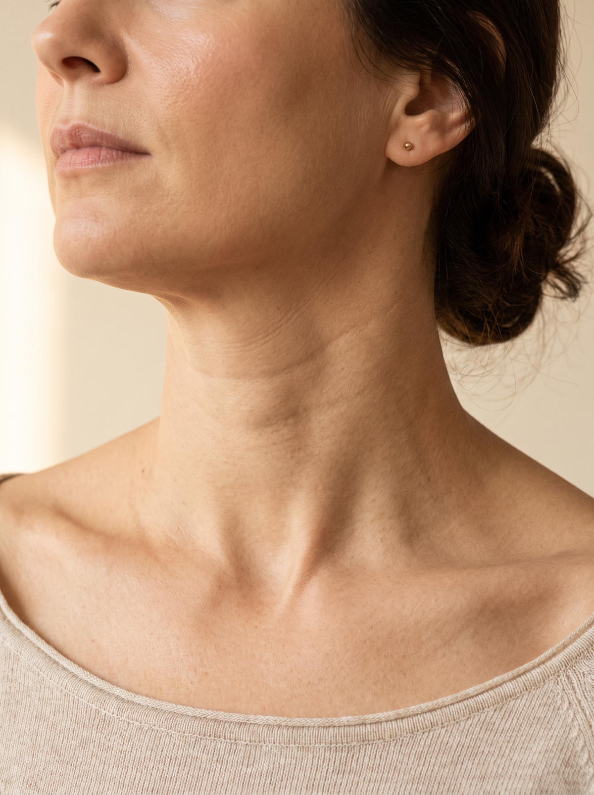Gros plan sur la ligne du cou et de la mâchoire d’une femme, lumière latérale douce